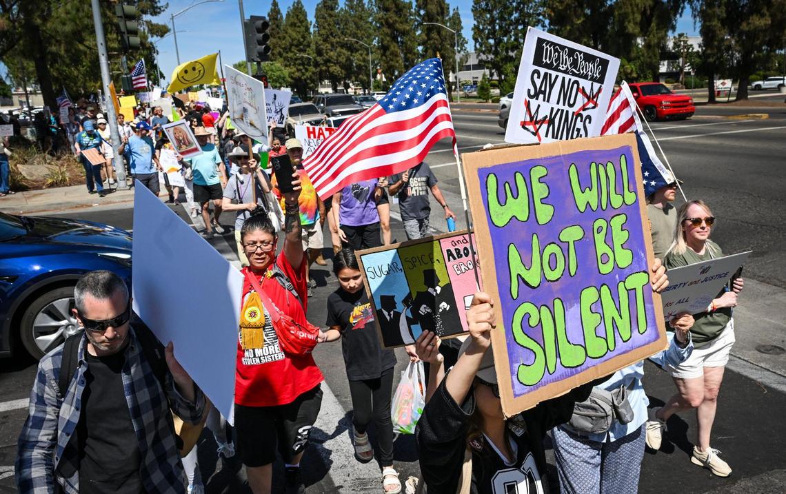 A group of protesters walks down Shaw Avenue in front of Fashion Fair mall during a “No Kings” protest against President Donald Trump’s policies in Fresno on Saturday, June 14, 2025.