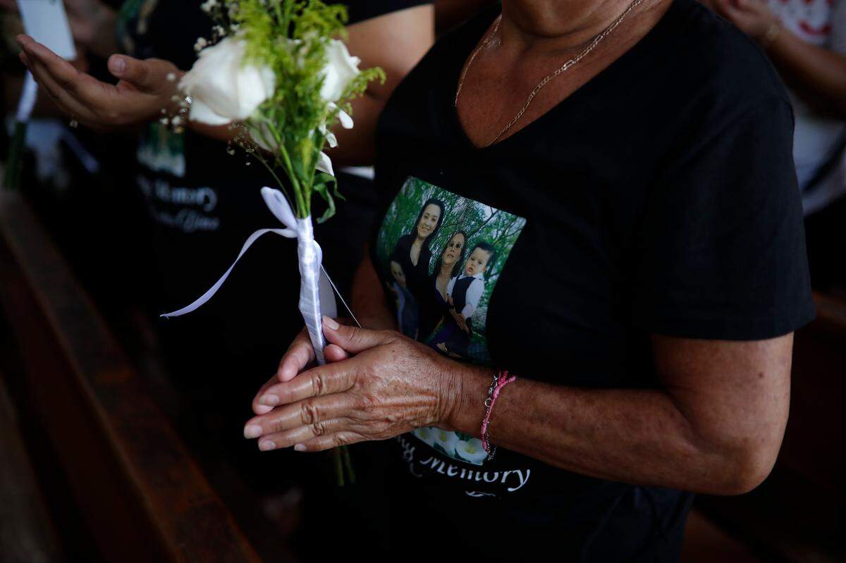 Una mujer usa una camiseta con una imagen de los integrantes de una familia que fueron víctimas de un hecho violento, este lunes durante su funeral en San Cayetano Istepeque, El Salvador. / A woman wears a T-shirt with an image of the members of a family who were victims of a violent act, this Monday during their funeral in San Cayetano Istepeque, El Salvador.