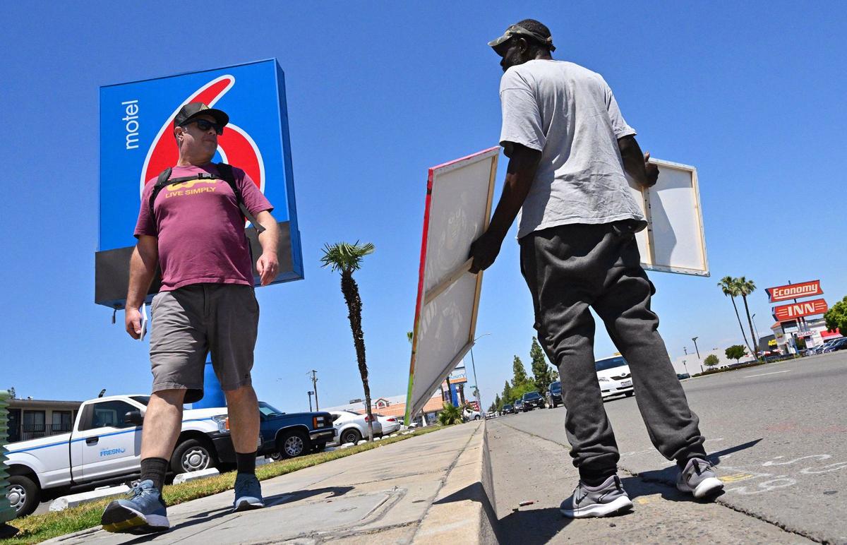 On his urban hike along Blackstone Avenue, Fresno Bee columnist Marek Warszawski, left, encounters Steven Smith who was selling his girlfriend’s art Wednesday, May 8, 2024 in Fresno. Smith said he expected to see more trees along Blackstone..