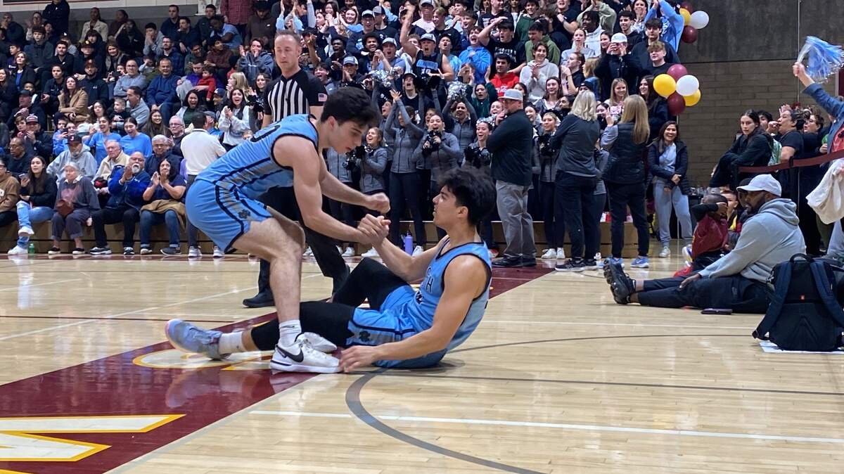 Clovis North’s Jordan Espinoza is helped up by Arman Arisian during a high school basketball game against Clovis West on Friday, Feb. 9, 2024.