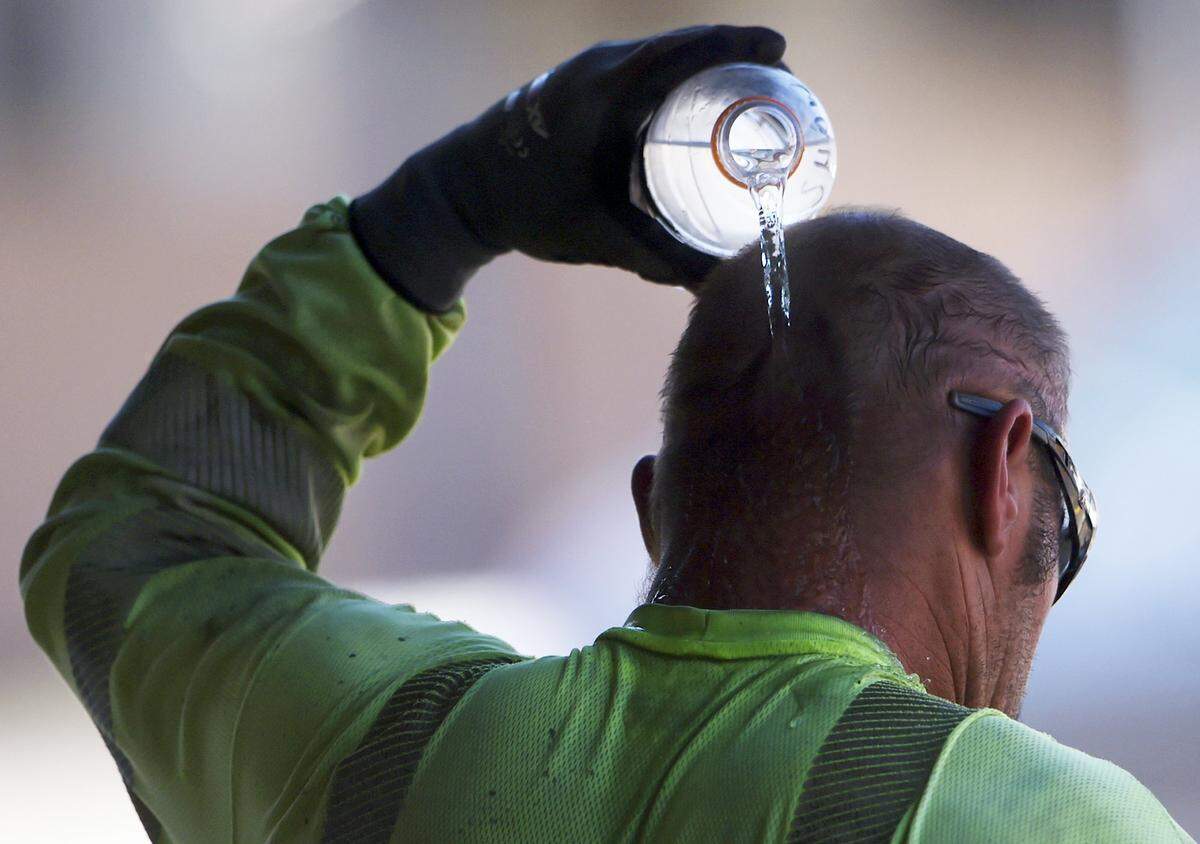 A construction worker pours a bottle of water over his head as he cools off in the shade at the end of the work day Wednesday, June 21, 2017 in Fresno.ERIC PAUL ZAMORA/THE FRESNO BEE
