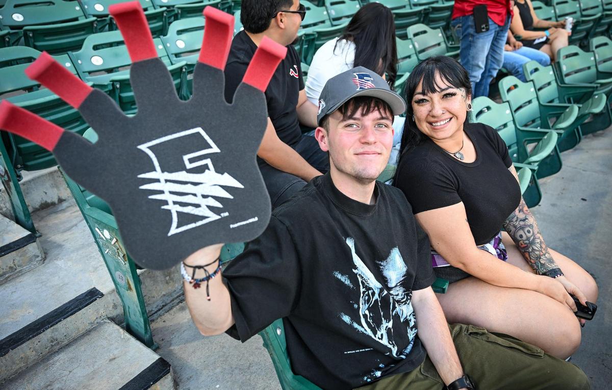 Fresno Grizzlies fans Brandon Breeland and Vanessa Deroma of Visalia wave their Grizzlies foam claw while cheering on the team during a game against the Modesto Nuts at Chukchansi Park in downtown Fresno on Wednesday, June 11, 2025.