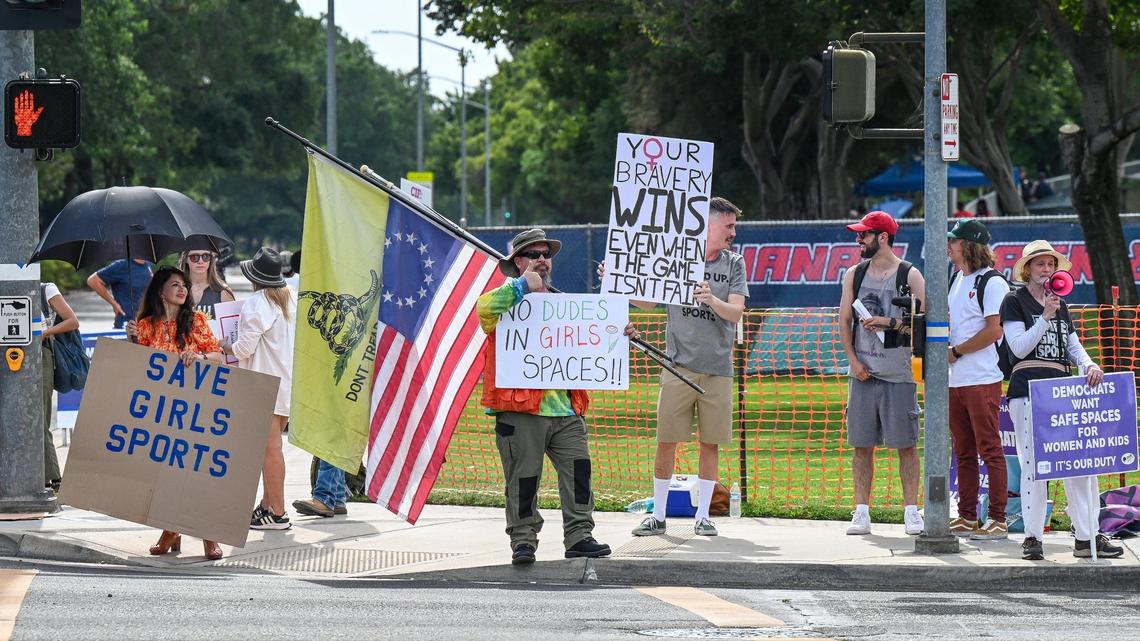 Protesters hold signs on the corner of Minnewawa and Nees avenues in Clovis near Veterans Memorial Stadium where a trans athlete was competing in the CIF state track & field finals on Saturday, May 31, 2025.