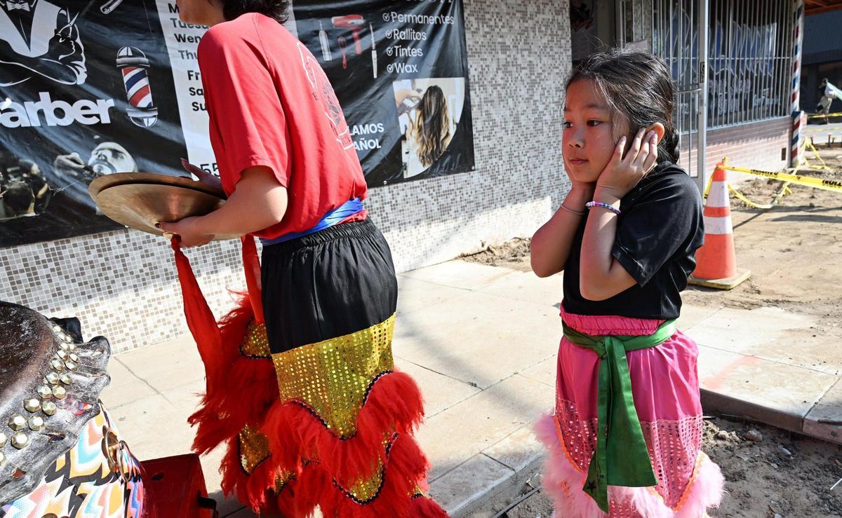 A young girl covers her ears from the loud music played by the Chinese New Year Lion Dancers visiting various businesses to welcome good luck and prosperity for the coming year Saturday morning, Jan. 25, 2025 in Fresno’s Chinatown.