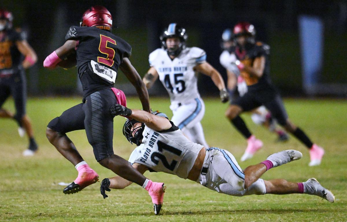 Clovis North’s Jackson Cinfel tries to tackle Clovis West’s Marshel Sanders on a punt return Friday, Oct. 13, 2023, in Clovis.
