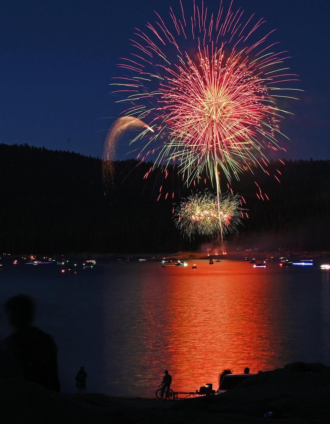 A cyclist and families watch from the shoreline at the 2022 Shaver Lake fireworks show Saturday, July 2, 2022 at Shaver Lake.