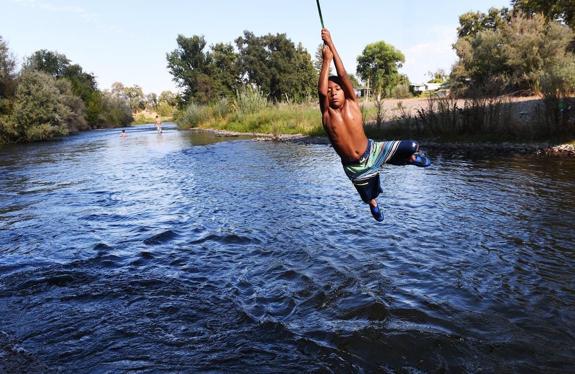 Kids keep cool swinging into the San Joaquin River beneath Highway 41 on Saturday, July 10, 2021 in Fresno. The National Weather Service issued an Excessive Heat Warning through 9 p.m. Monday.