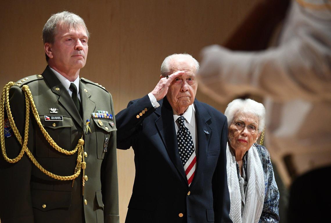 World War II Army veteran Vernon Schmidt, 96, salutes the posting of the colors, with wife, Violet, and Czechoslovakia Army Colonel Jindrich Hacker, left, during a ceremony, Thursday March 10, at the Clovis Veterans Memorial District, where he was presented the Honorary Commemorative&nbsp;Medal for his merits in liberating Czechoslovakia in May 1945 and Holocaust survivors from the Flossenburg concentration camp.