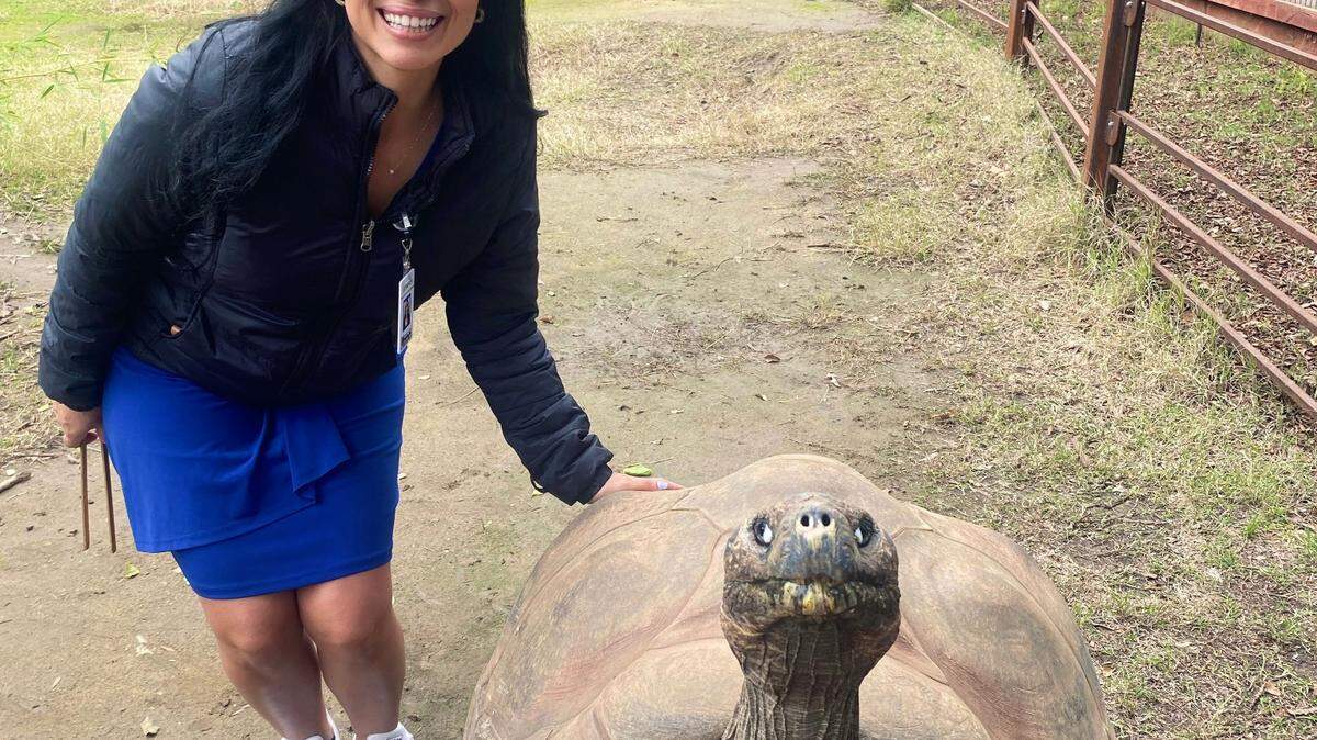 Jennifer Ortega posing with Knobby, a 64-year-old Galapagos tortoise at the Fresno Chaffee Zoo.