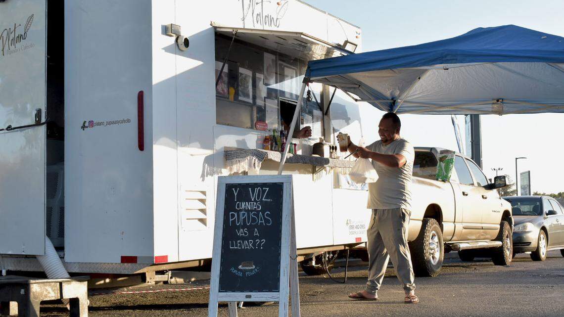 Un hombre recibe su pedido en ‘Plátano, Pupusas Y Cafecito’, en Madera, el 7 de octubre. El camión de comida salvadoreña opera en el lote de una gasolinera Chevron en Cleveland Avenue y Highway 99 en la ciudad de Madera, donde los propietarios dicen que pudieran quedarse finalmente, a pesar de residir en Chowchilla.