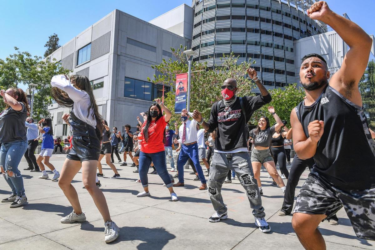 Fresno State students joined by University President Saúl Jiménez-Sandoval, background center, erupt into a flash mob of dancing during a noontime event called “Bulldogs Joyful Together” on campus near the Henry Madden Library on Wednesday, Sept. 8, 2021. Organizers called the event an opportunity for students, staff and faculty to interact and come together in celebration of our return to campus, after nearly a year and a half of working from home and distance learning.