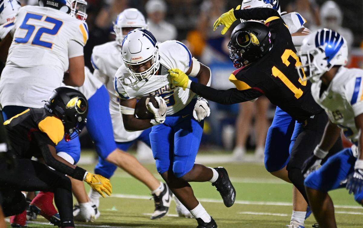 Tulare Union's Brody Moreno, right, gets a hand on Bakersfield Christian's Richlyn Gooden, center, on a run Friday, Sept. 26, 2025 in Tulare. Bakersfield Christian beat Tulare Union 30-7.