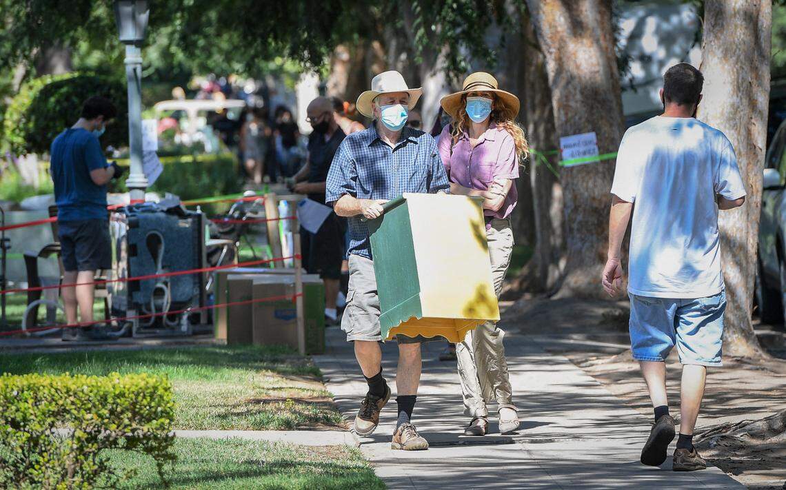 Tim and Alison Simmers carry an end table to their car after making a purchase during the annual Harvard block sale in Fresno on Saturday, July 11, 2020. The sale was moved from May due to the coronavirus pandemic, but was still discouraged by city officials.