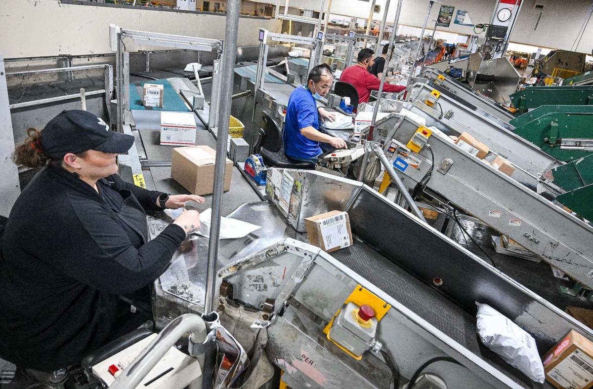 Lisa Gutierrez checks labels on packages at the United States Postal Service’s Fresno Mail Processing and Distribution Center on E Street in Fresno on Thursday, Dec. 12, 2024.