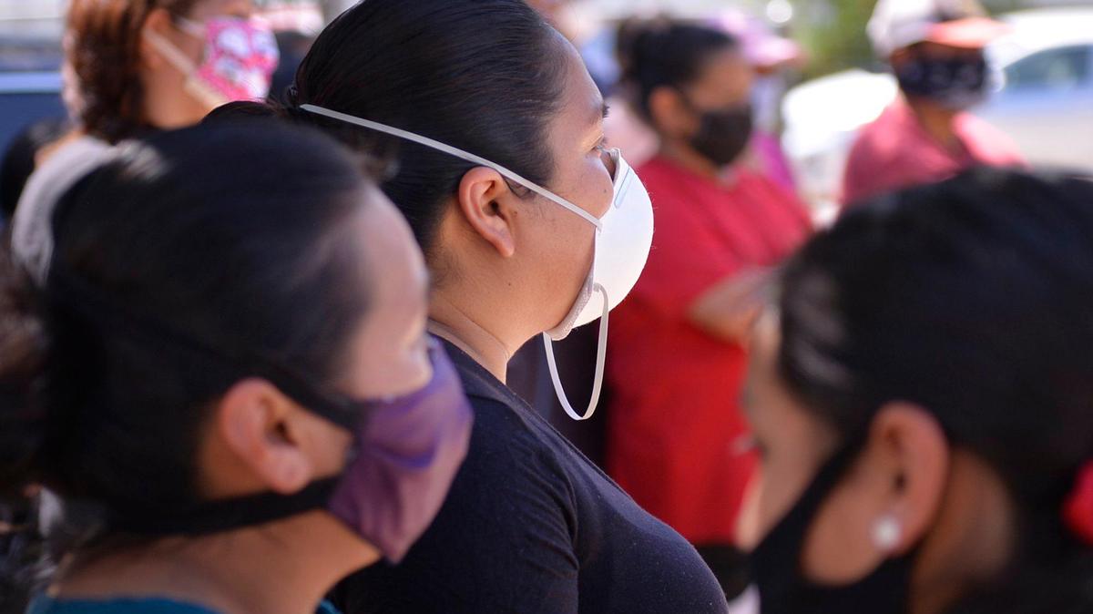 Masked farmworker families stand waiting May 9, 2020 near Rolinda, CA.