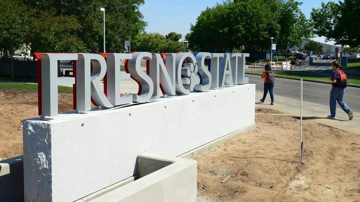 Students walk by a gateway sign at the entrance to Fresno State at Maple and Shaw avenues.