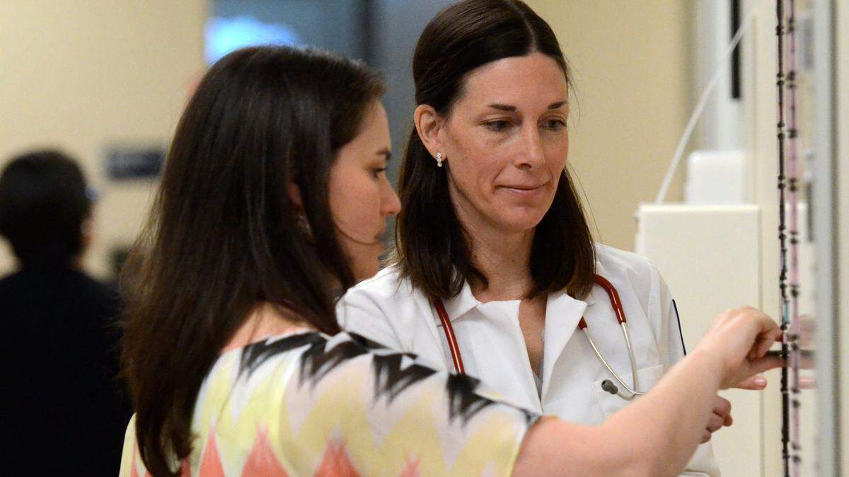 Christian Faulkenberry-Miranda, a pediatric physician, center, with Anna Ekstrom, left, D.O. (Doctor of Osteopathic Medicine), residents from UCSF Fresno, go over a scheduling chart in the pediatric clinic at the Deran Koligan Ambulatory Care Center.