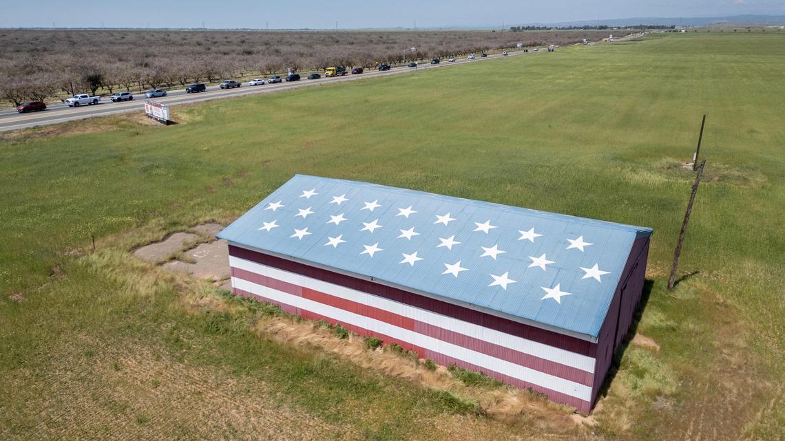 The Stars and Stripes barn sits in the foreground as traffic begins to back up on southbound Highway 41 in Madera County on Wednesday, April 9, 2025. Both Highway 41 and Avenue 12 will be going under major widening construction projects in the coming months and years.