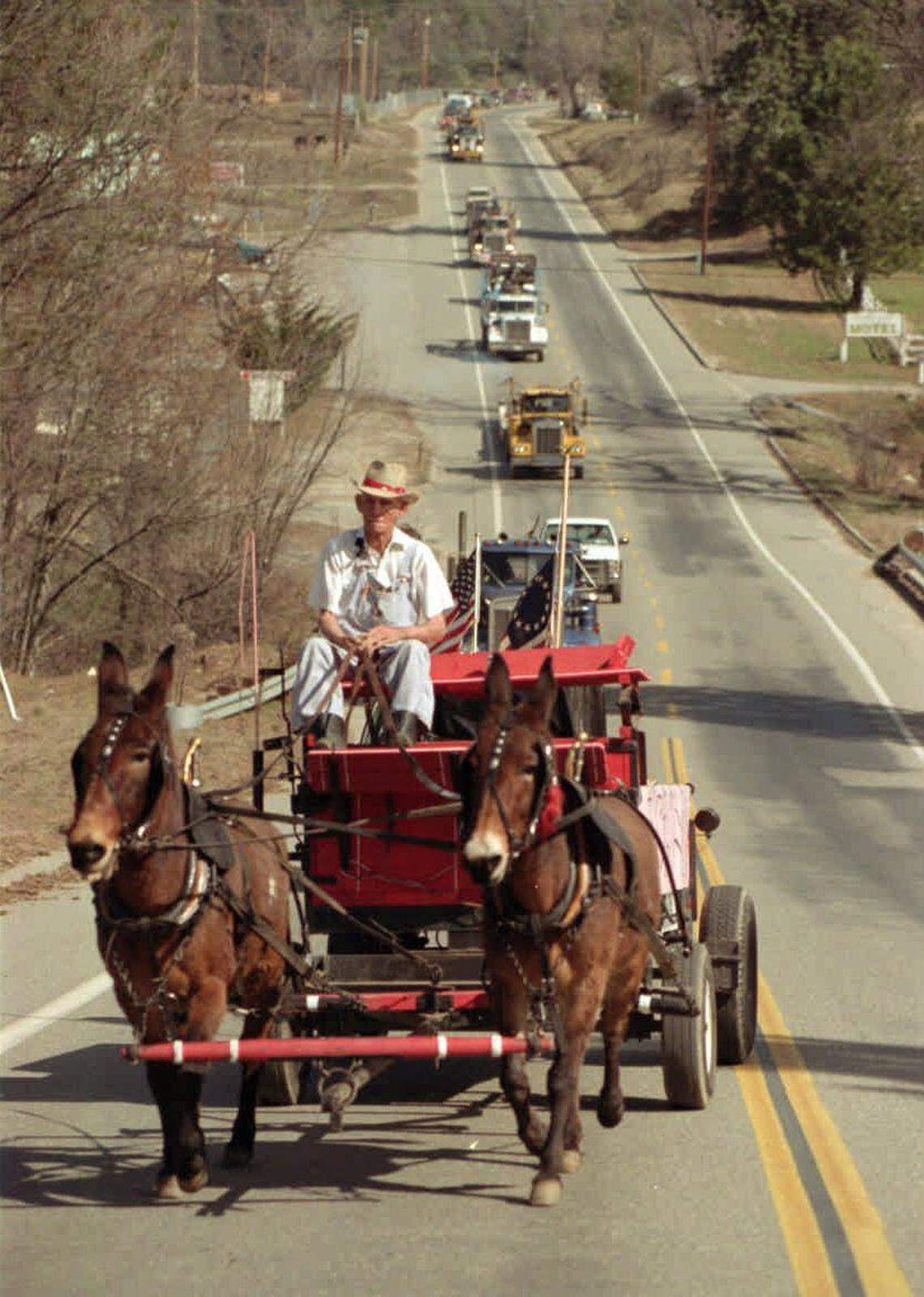 Charlie Rand drives a wagon with a coffin in the back as a symbolic gesture for the closure of the North Fork sawmill in February 1994. Behind him is a procession of logging trucks headed for downtown North Fork.