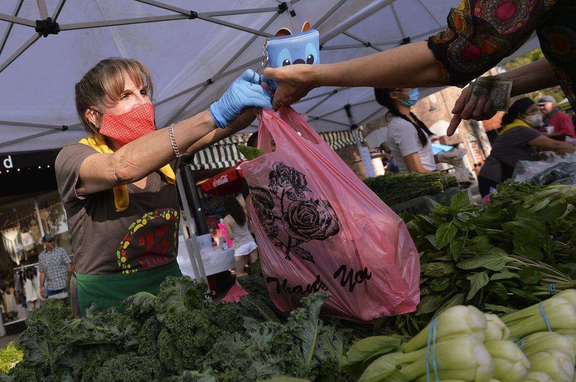 Sheri Cooley sells produce on the evening of the year’s first Friday night Old Town Clovis Farmers Market in 2020..