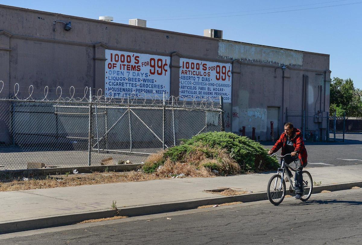 A man rides his bike by a discount store in west Fresno on Monday, June 8, 2020. The building had one time been a Safeway grocery store, which was part of a bustling economy in west Fresno. In recent decades, however, businesses moved north, leaving behind blight and decay.