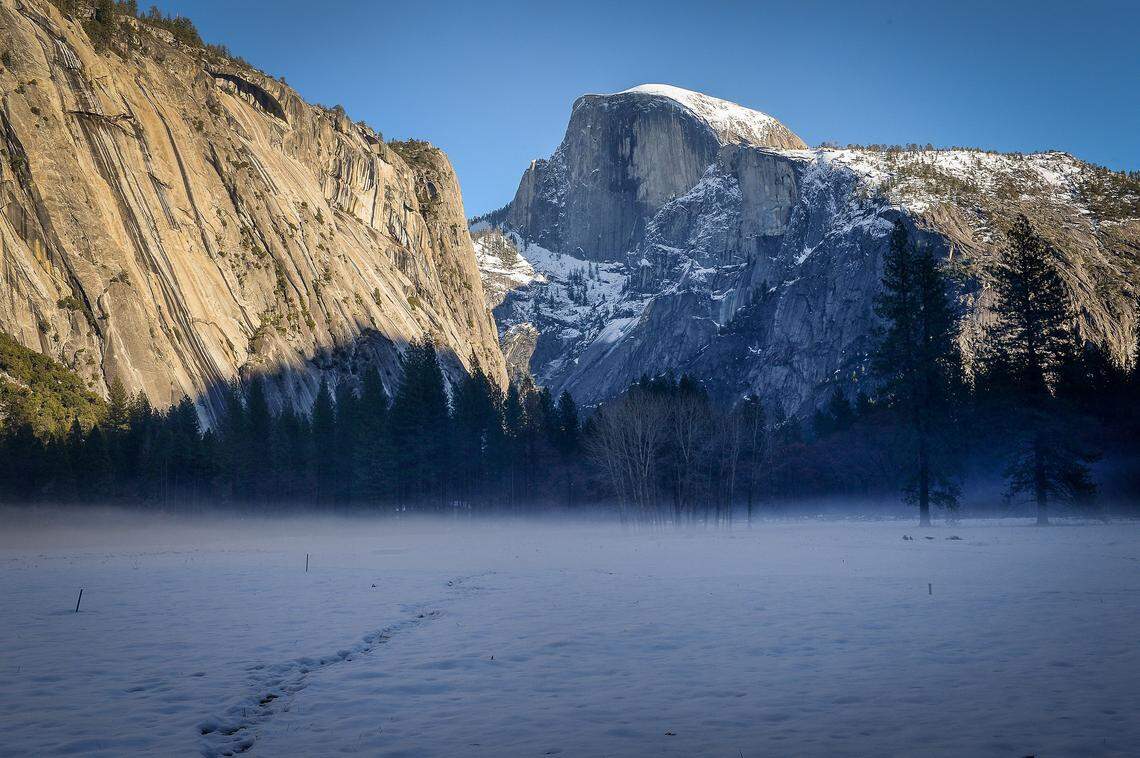 Half Dome stands off in the distance as light fog rises from the Ahwahnee Meadow after snow dusted Yosemite National Park over the past few days, on Monday, Dec. 9, 2019.