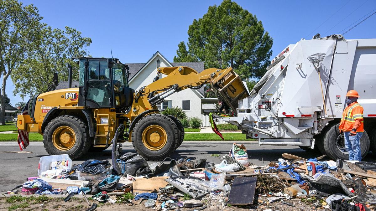 A city worker uses “the Claw” frontloader to scoop up residential trash left out on a street in southeast Fresno during Operation Cleanup in Fresno on Monday, April 8, 2024.