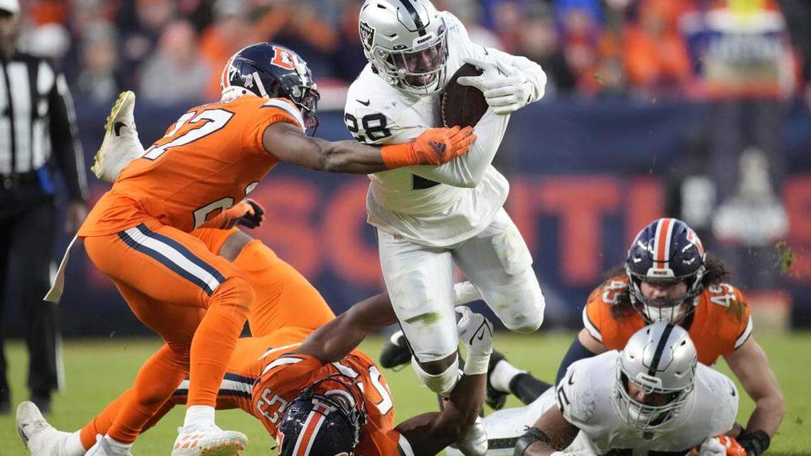 Las Vegas Raiders running back Josh Jacobs runs against Denver Broncos cornerback Damarri Mathis during the second half of an NFL football game in Denver, Sunday, Nov. 20, 2022.