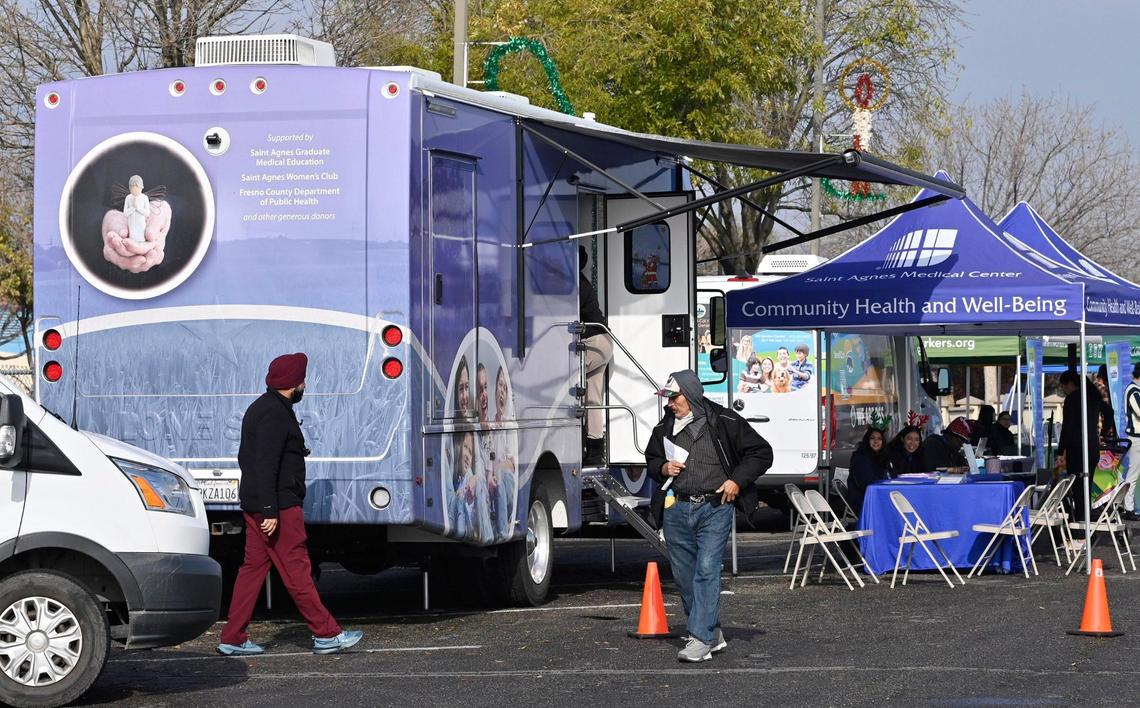 The Saint Agnes Mobile Health Unit van, left, is seen offering services during a Covered California event held in Mendota’s Rojas Pierce Park Thursday, Dec. 12, 2024.
