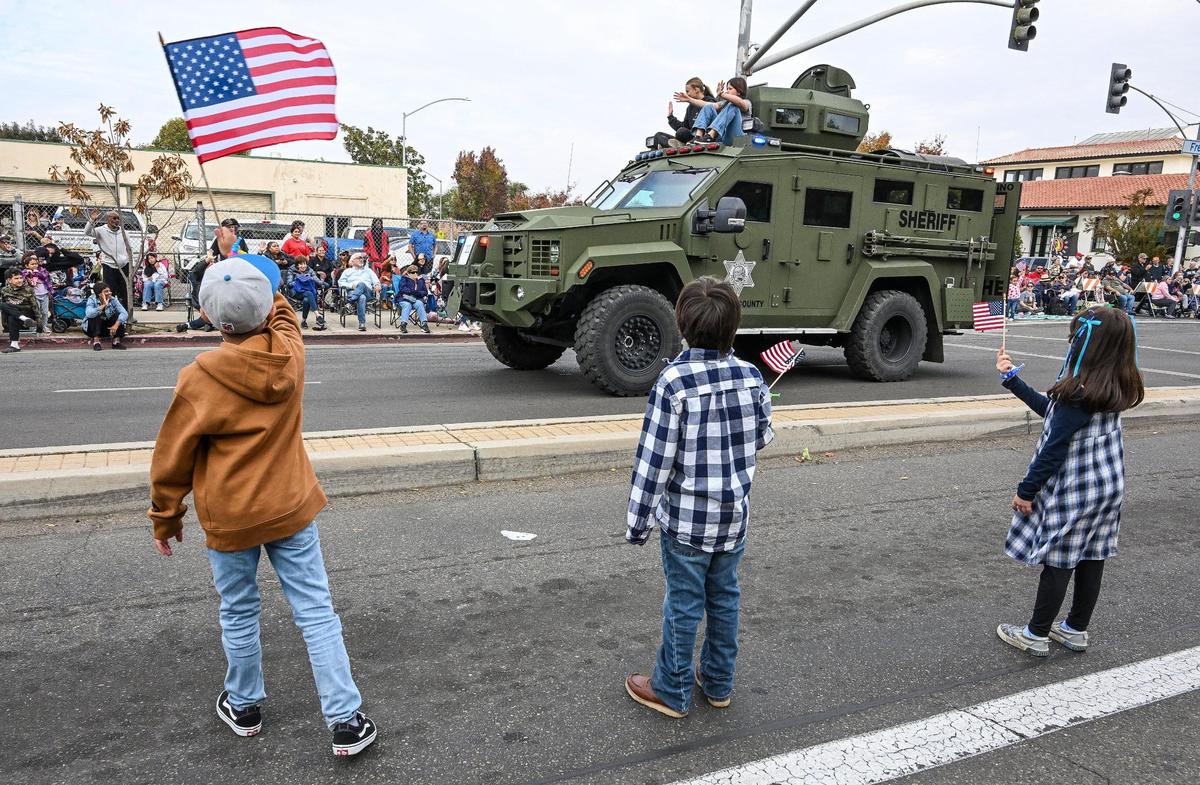 Kids wave flags as a Fresno County Sheriff’s Department armored vehicle passes during the 105th annual Central Valley Veterans Day Parade in downtown Fresno on Monday, Nov. 11, 2024.