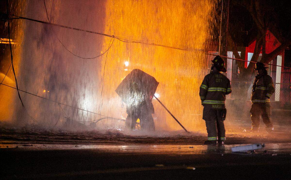 Fire crews work to turn off water gushing from fire hydrant after a crash at the Olive and Recreation Avenues intersection on Sunday, Nov. 28, 2021.
