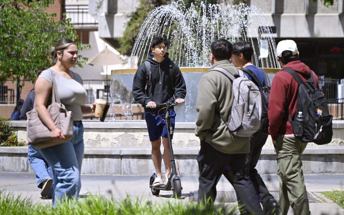 A student rides his motorized scooter past Fresno State's fountain Monday, April 27, 2026 in Fresno. The university will begin a ban on all motorized scooters, skate boards and bikes starting August 19 this year.