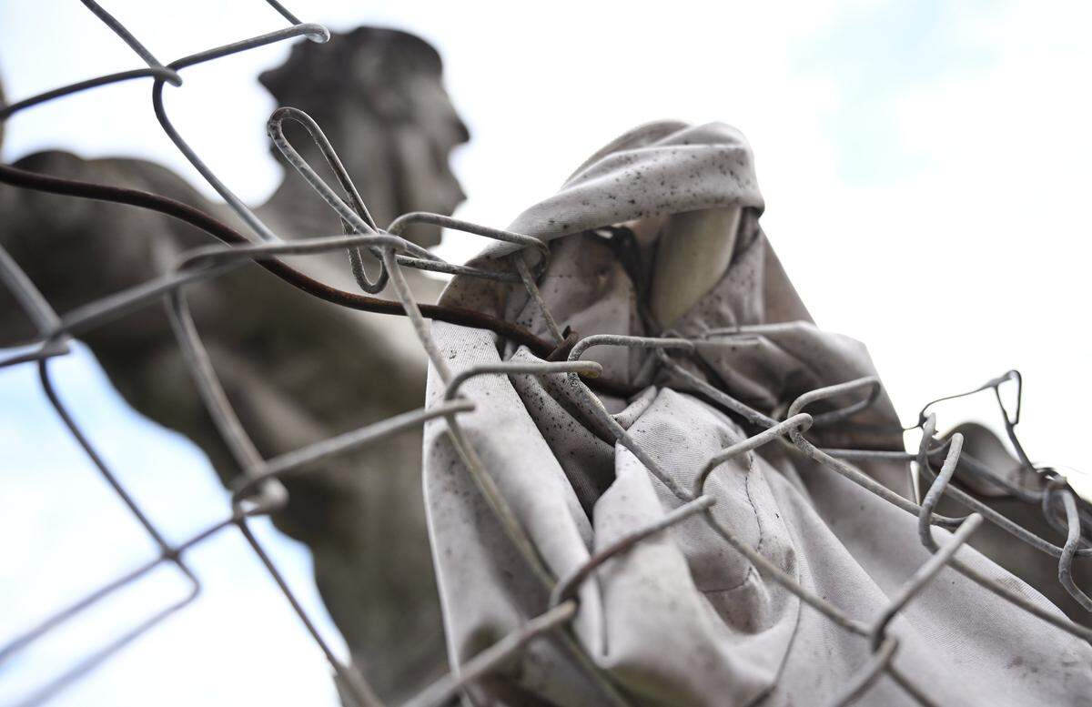 A weathered tarp is seen along a chainlink fence with the mold for the David of Sassoon statue in the background, Thursday, Jan. 22, 2026 in Fresno.