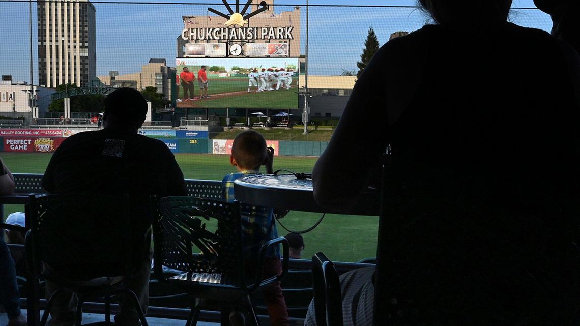 Fans watch players take the field on the new scoreboard at the Fresno Grizzlies season opener against the Stockton Ports Friday, April 8, 2022 at Chukchansi Park in Fresno.