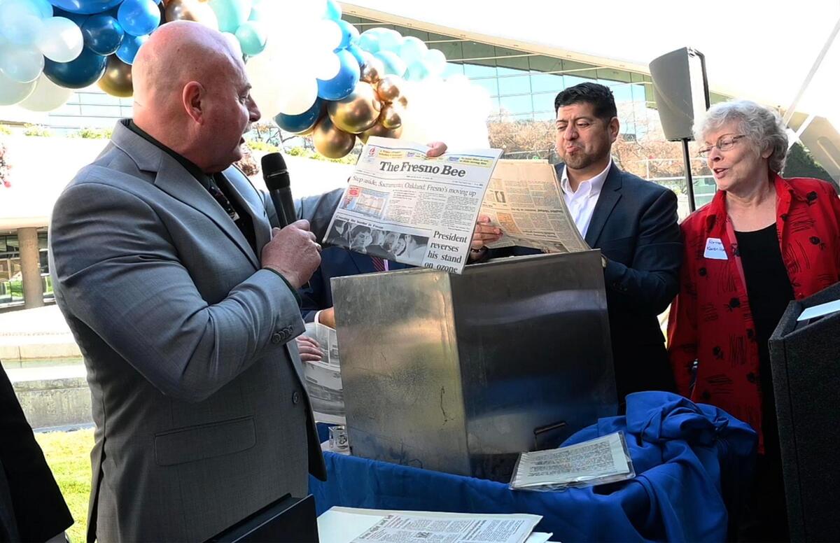 Fresno Mayor Jerry Dyer, left, holds up a copy of the Fresno Bee with an article about the City of Fresno moving up to number 8 among top 10 cities in the state as former Fresno Mayor Karen Humphrey, right, and council member Luis Chavez look at another issue of the Bee as the contents of a 30-year old time capsule are revealed Tuesday, Dec. 13, 2022 in Fresno. A new time capsule will be locked away and retrieved in another 30 years.