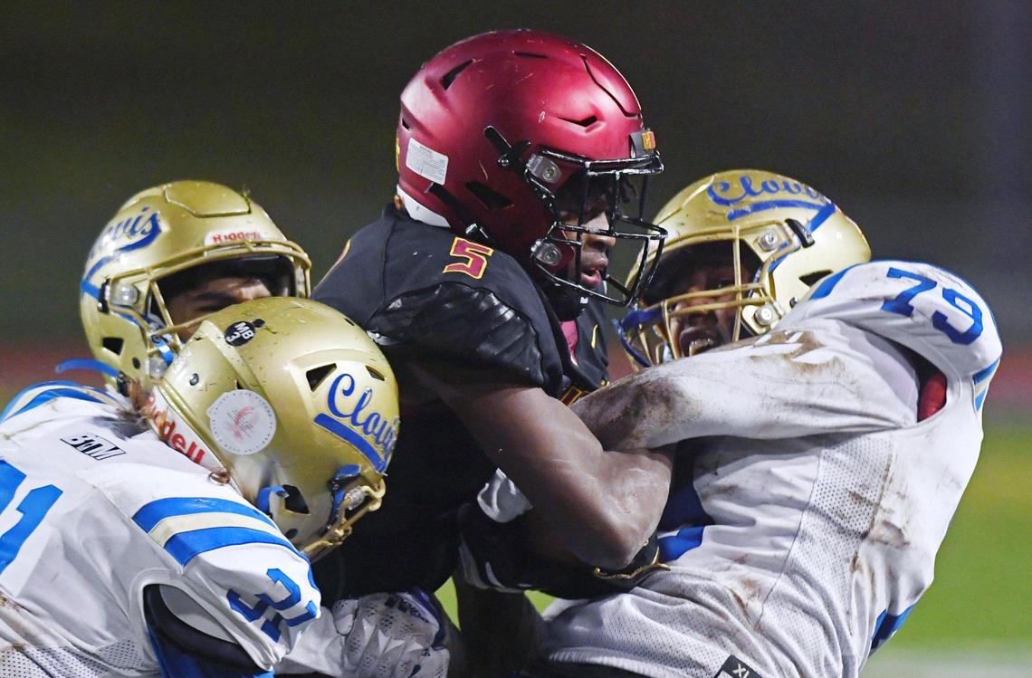 Clovis West’s Marshel Sanders, center, is brought down by Clovis High’s defense in first quarter action of a central Section DI quarterfinal Thursday, Nov. 10, 2022 in Clovis.