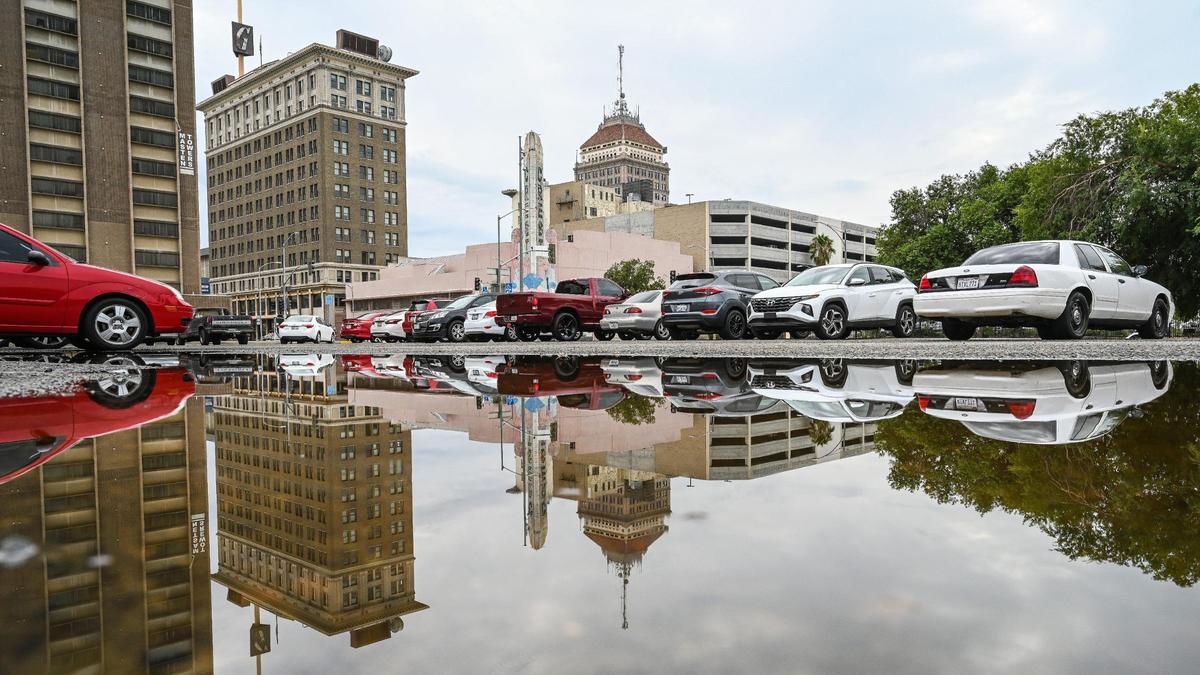 Downtown Fresno is reflected in a puddle in a parking lot following a morning of rain showers on Friday, Aug. 5, 2022.