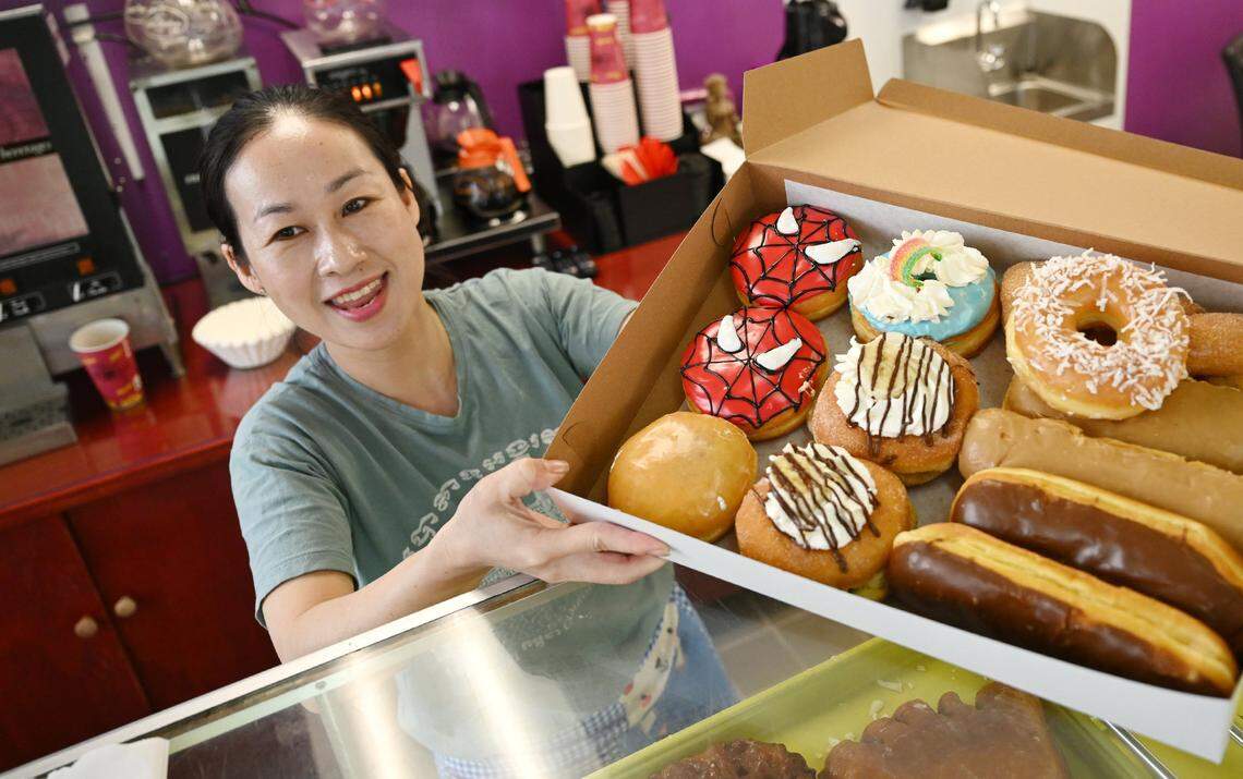 Thary Ky offers a box of selected donuts for a customer at City Donuts which she and her sister opened in the former Supreme Donuts location at the corner of Palm and McKinley avenuess. Photographed Wednesday, Oct. 22, 2025 in Fresno.