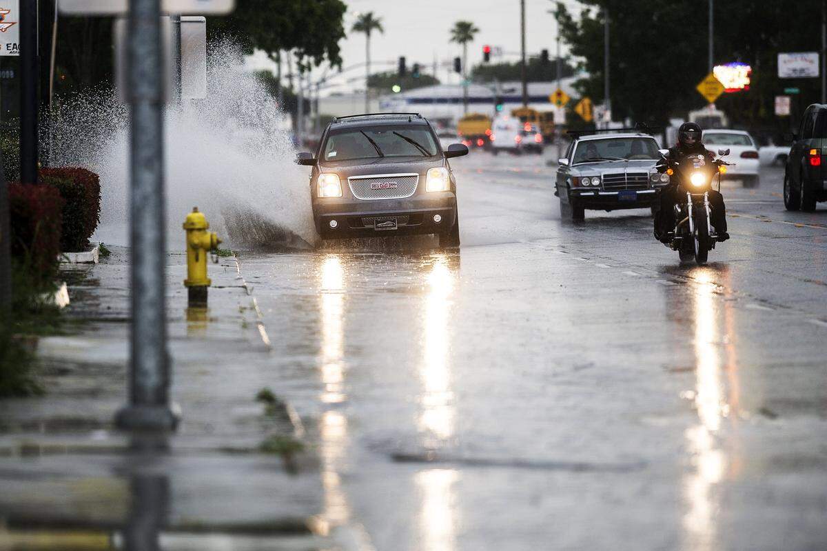 An SUV drives through standing water in the flooded right lane of Martin Luther King Jr. Way during a heavy rainstorm in Merced, Calif., Thursday, May 7, 2015. 