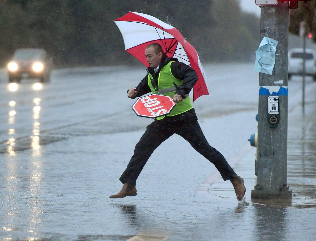 Garfield Elementary crossing guard Kai Dill tries a leap across the flooding street on Peach Ave.