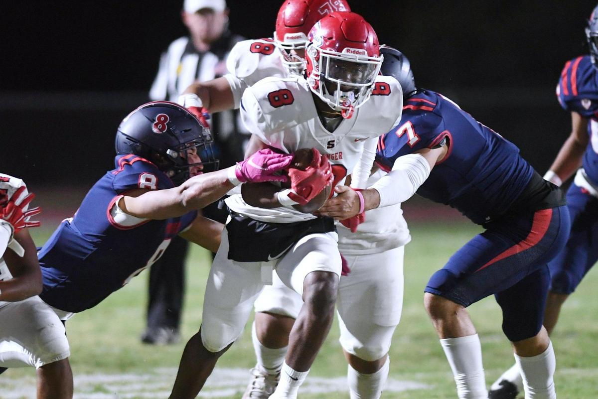 Sanger’s Bryson Baker, center, breaks through San Joaquin Memorial’s defense of Brandon Ramirez, left, and Brandon Rangel, right, Friday, Oct. 28, 2022 in Fresno. Memorial led 28-14 at halftime.