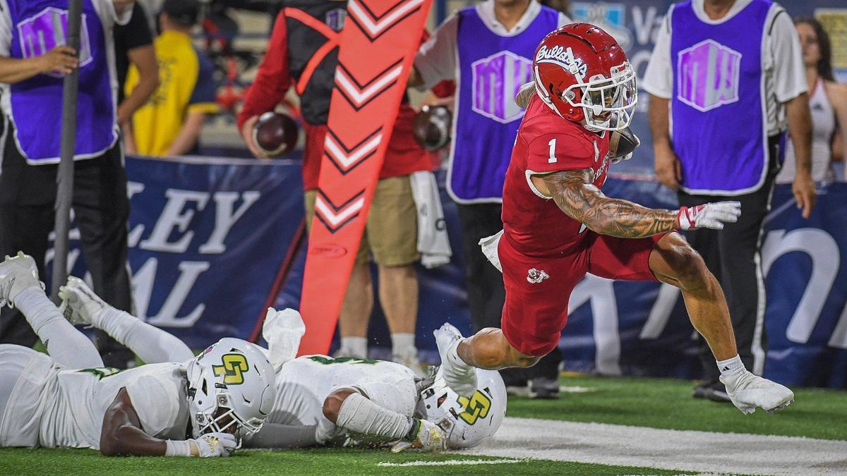 Fresno State’s Nikko Remigio, right, jumps away from Cal Poly defenders on a long pass play during their game at Valley Children’s Stadium on Thursday, Sept. 1, 2022.