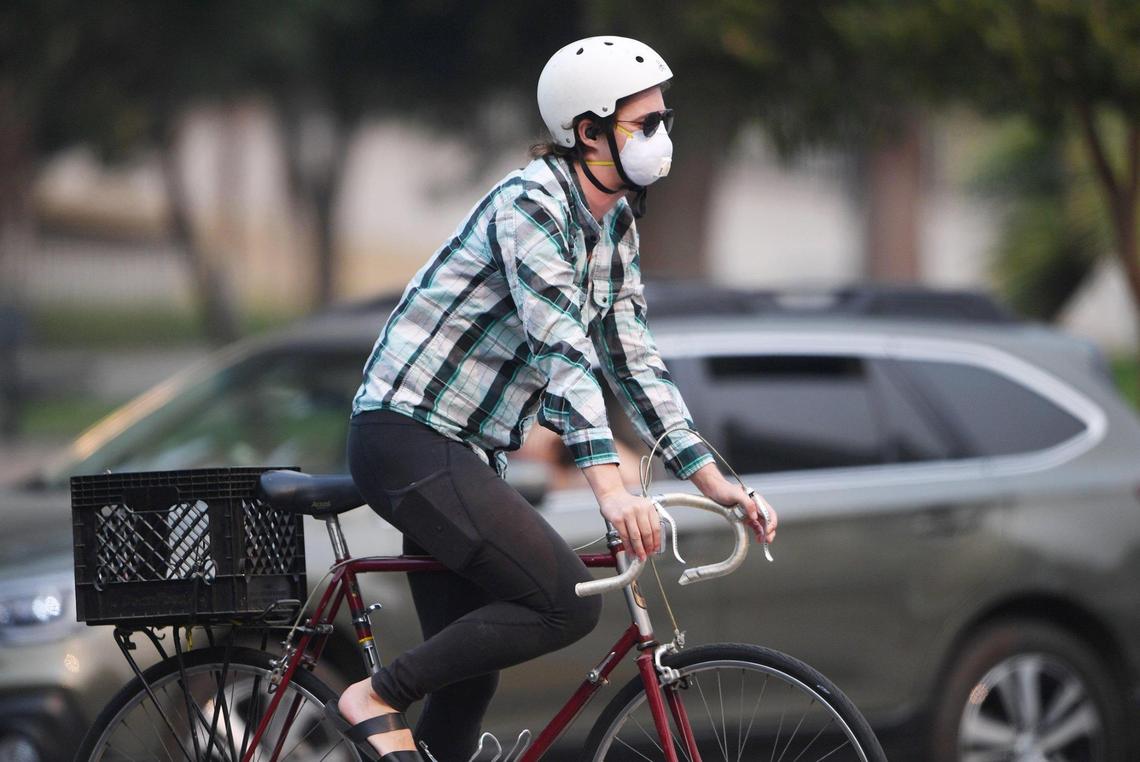A cyclist rides through an intersection downtown as smoke from wildfires hundreds of miles away blankets the Fresno area Thursday, Aug. 19, 2021 in Fresno.