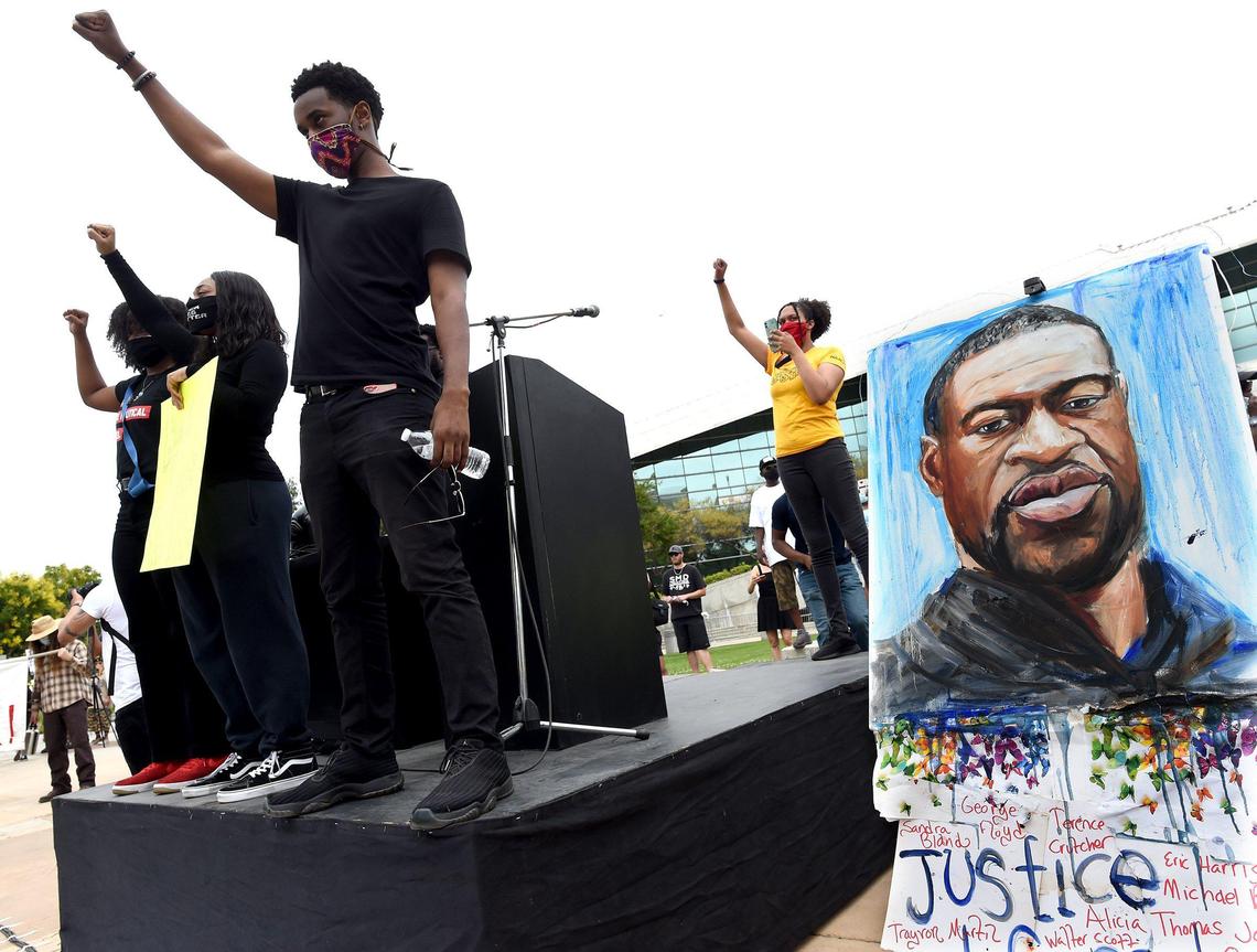 Speakers join with raised fists during the rally to protest the death of George Floyd, right, at city hall, May 31, 2020.
