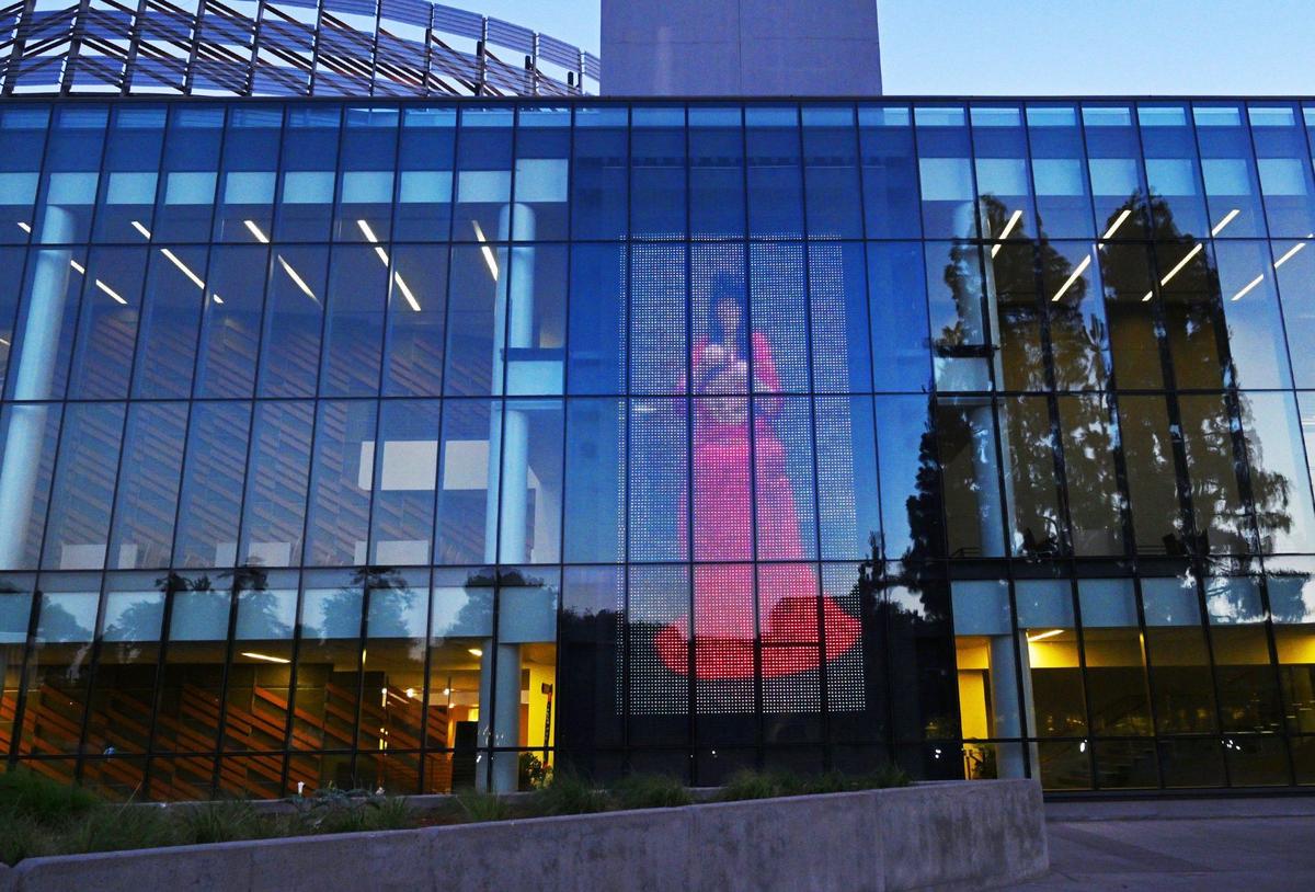 Lois Conner, a North Fork Mono artist, weaving a basket from start to finish over the course of 12 months, is shown as the 700 foot tall LED display Lady In Red, seen on the northern exterior of Fresno State’s Library, Thursday, 13, 2024 in Fresno.