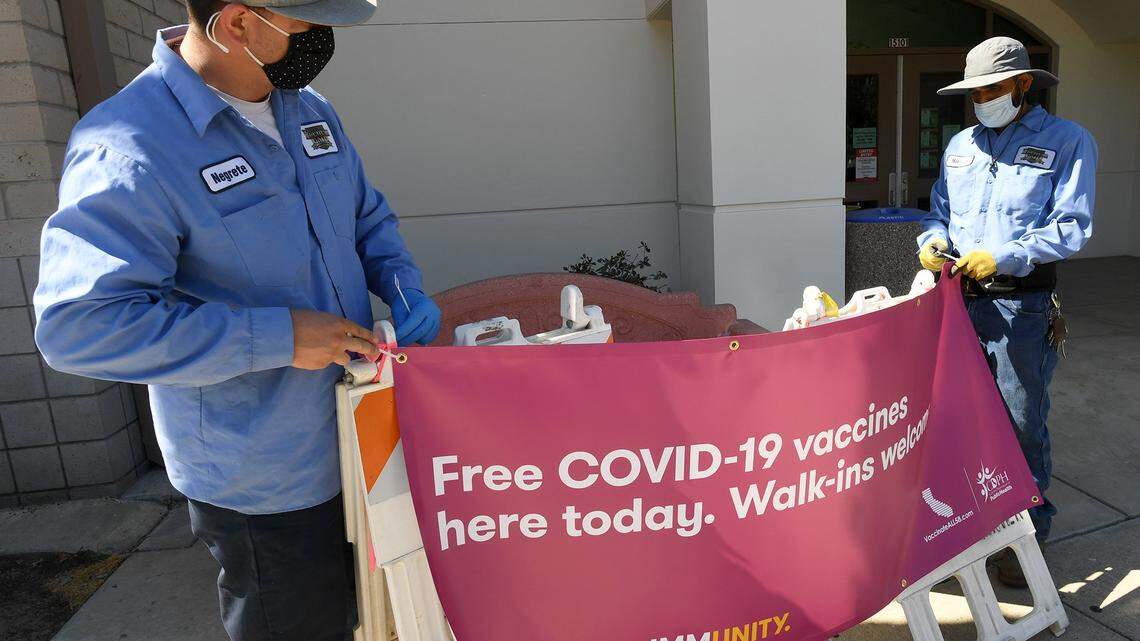 Kerman City workers Dean Negrete, left, and Nirmal Sidhu, set up banners for the Covid-19 vaccination set up at the Kerman Community Center, June 9, 2021.