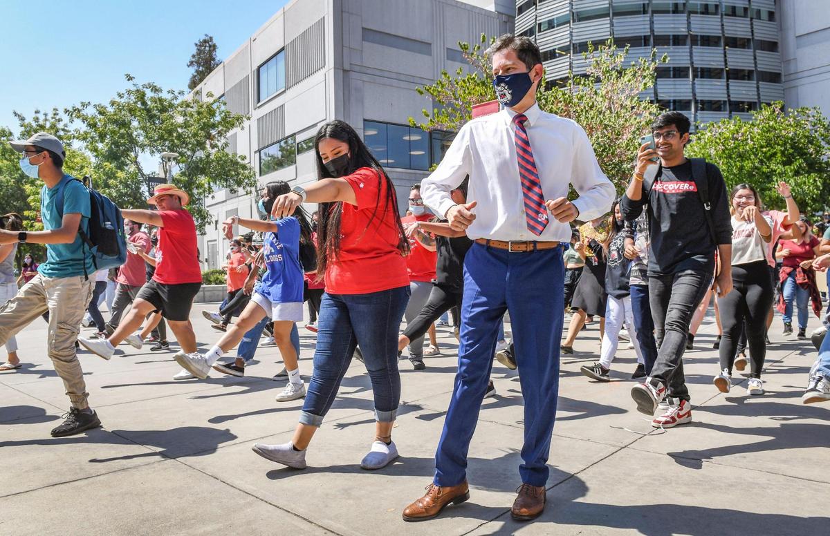 Fresno State students joined by University President Saúl Jiménez-Sandoval, right center, erupt into a flash mob of dancing during a noontime event called “Bulldogs Joyful Together” on campus near the Henry Madden Library on Wednesday, Sept. 8, 2021. Organizers called the event an opportunity for students, staff and faculty to interact and come together in celebration of our return to campus, after nearly a year and a half of working from home and distance learning.