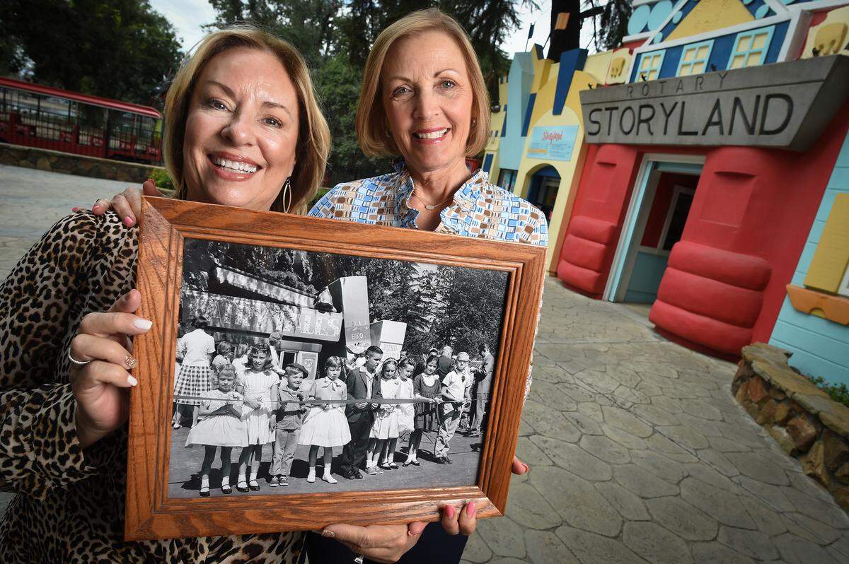Kathy Solt-Winter, left, and Marcia Pell-Nash hold a photograph of themselves as children (Solt-Winter, second from left; Pell-Nash, second from right) during the ribbon cutting for Storyland on May 19, 1962. Solt-Winter still has her piece of the pink ribbon from the special day tucked away in an album.