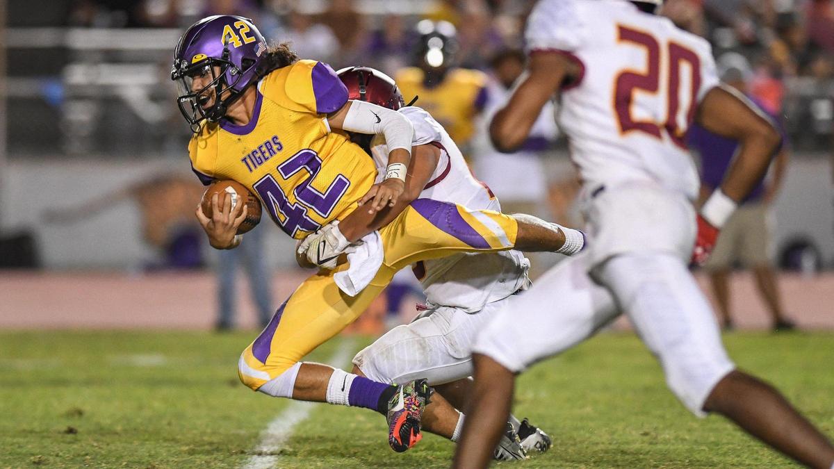 Lemoore quarterback Ty Chambers, left, gets a few yards up the middle on a keeper before being brought down by Clovis West in the second half of their game at Lemoore High on Friday, Sept. 2, 2022.