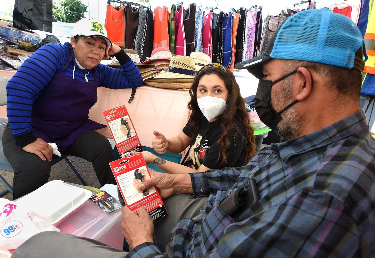 Valeria Rodriguez-Pedroza, a community advocate, center, talks with street vendors Francisco Matias, right, and his wife, Reina Acevedo, about the use of pepper spray. Advocates are discussing safety with vendors following the shooting death of street vendor Lorenzo Perez.